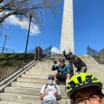 people gathered around a memorial biking together for the bike month challenge
